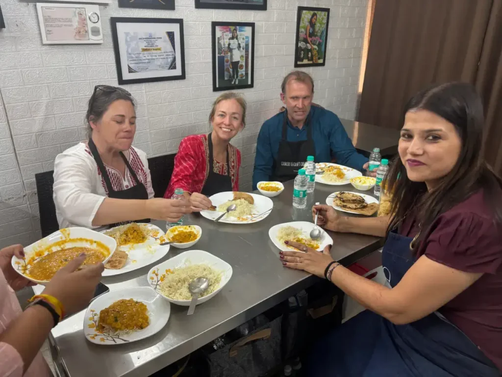Male and female international tourists enjoying a traditional Indian cooking class and homemade meal with a local cooking instructor in Agra, India.
