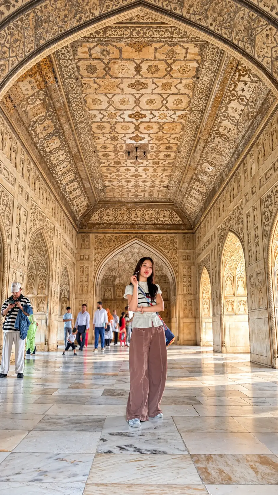 Female tourist posing inside an ornate Mughal hall at Agra Fort in India