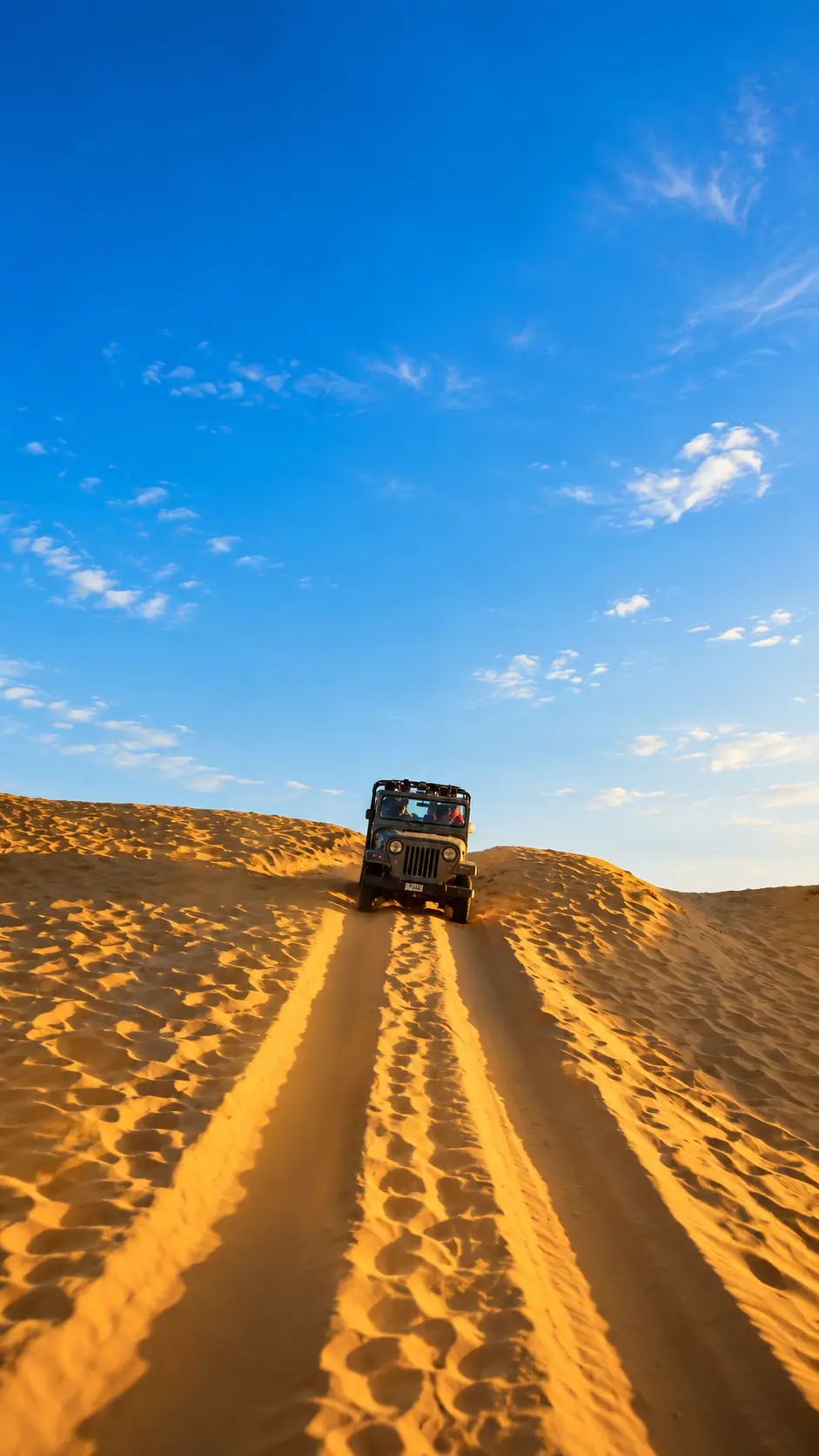 Jeep driving over golden sand dunes during a desert safari