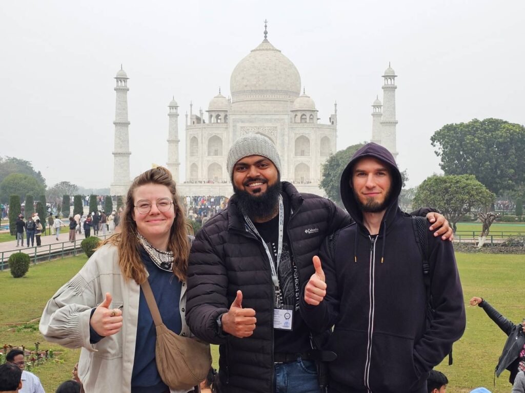 Cultures of India: Exploring the Soul of a Timeless Civilization 16 Kamran Khan, a tour guide from Agra Trip Packages, standing with two international travelers in front of the Taj Mahal in Agra, India.