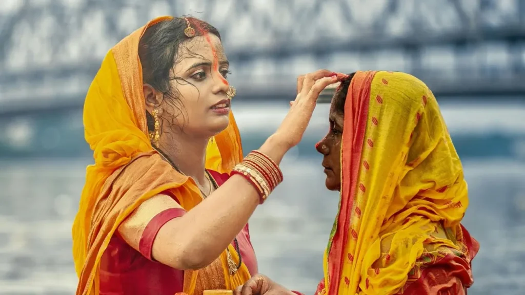 Cultures of India: Exploring the Soul of a Timeless Civilization 8 A woman in traditional Indian attire applies a ceremonial tilak to another woman during a Hindu religious ritual, symbolizing devotion, blessings, and India's vibrant cultural traditions.