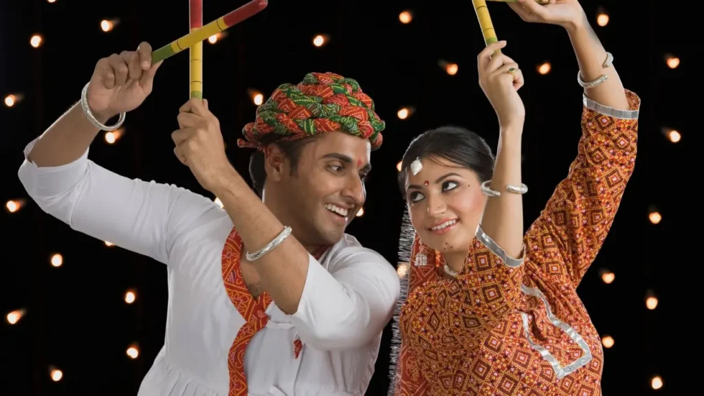 Cultures of India: Exploring the Soul of a Timeless Civilization 6 A man and woman in traditional Gujarati attire performing Dandiya Raas during the Navratri festival, celebrating India's vibrant folk dance and cultural heritage.
