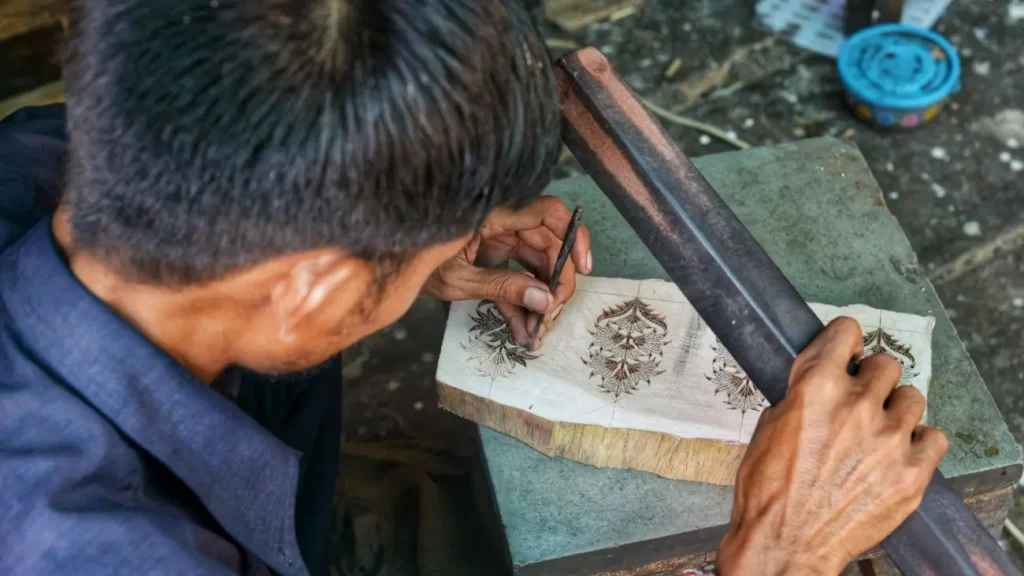 Cultures of India: Exploring the Soul of a Timeless Civilization 11 An Indian artisan hand-carving intricate floral patterns on a wooden block, showcasing traditional craftsmanship and India's rich handicraft heritage.