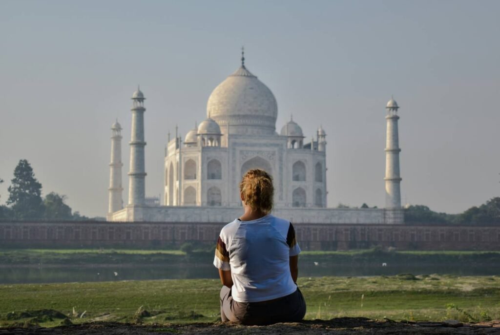 Tourist sitting at Mehtab Bagh overlooking the Taj Mahal across the Yamuna River in Agra, Uttar Pradesh, India.